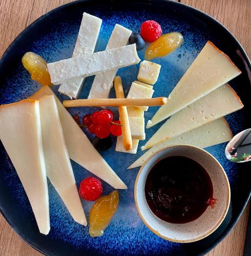 a blue plate with different types of cheese and fruit at MYND Adeje in Adeje