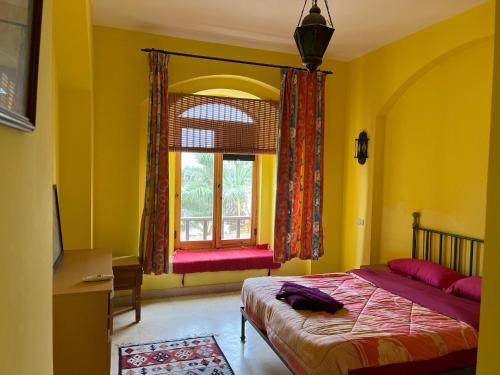 um quarto com paredes amarelas, uma cama e uma janela em El Gouna, Red Sea, Egypt, West Golf 2 Bedroom Flat em Hurghada