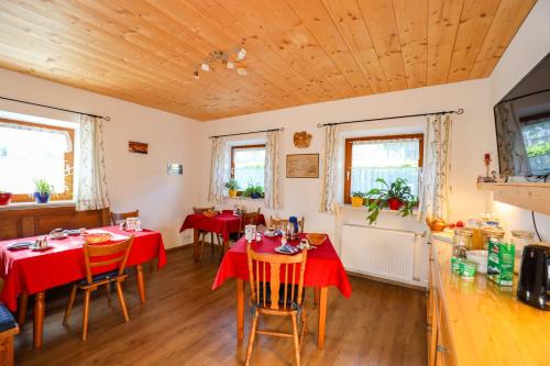 ein Esszimmer mit Tischen, Stühlen und Holzdecken in der Unterkunft Landhaus Freund in Berchtesgaden