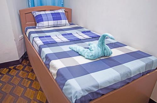 Una pequeña cama con un juguete de dinosaurio azul. en Providence Travellers Inn & Spa, en Tagbilaran City