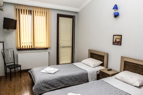 una habitación de hotel con 2 camas y una silla en Tbilisi Tower Apartment, en Tiflis