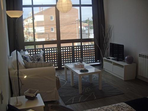 - un salon avec un canapé, une table et une grande fenêtre dans l'établissement Beach Castelldefels, à Castelldefels