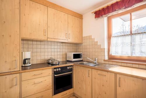 a kitchen with wooden cabinets and a sink and a microwave at Ciasa Tlara App Alma in San Vigilio Di Marebbe