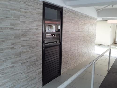 a wall with a black door on a brick wall at Apartamento na Praia do Morro in Guarapari