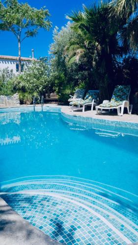 a swimming pool with chairs and blue water at Cortijo Paraiso in Cúllar de Baza