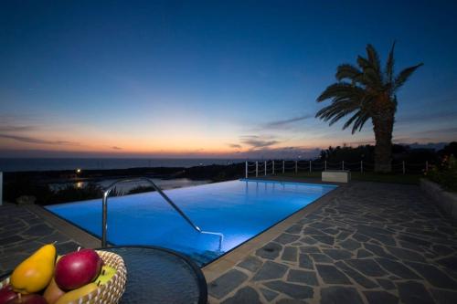 a swimming pool with a bowl of fruit next to it at Ionian Blue Luxury Villas in Svoronata