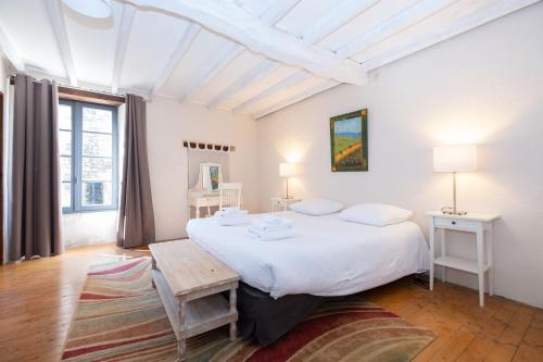 a white bedroom with a large bed and a table at Montboulard in Soyaux