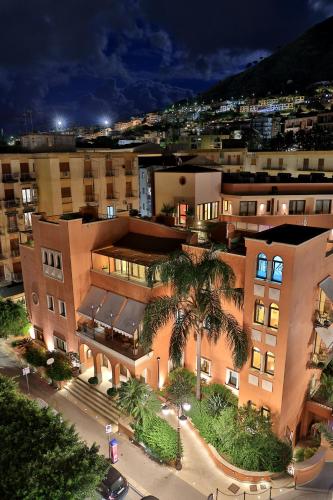a large building with a palm tree in front of it at Artemis Hotel in Cefalù