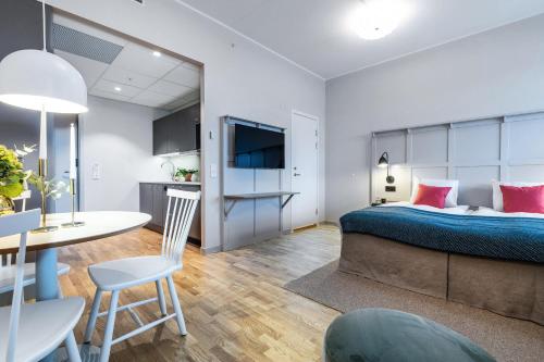 a bedroom with a bed and a table and a kitchen at Biz Apartment Bromma in Stockholm
