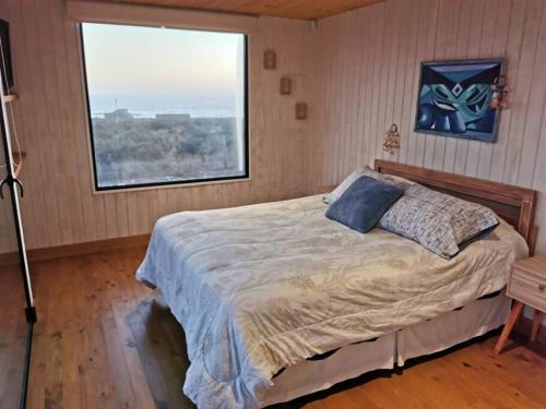 a bedroom with a bed with a large window at Cómoda Casa en la Playa in Guaquen