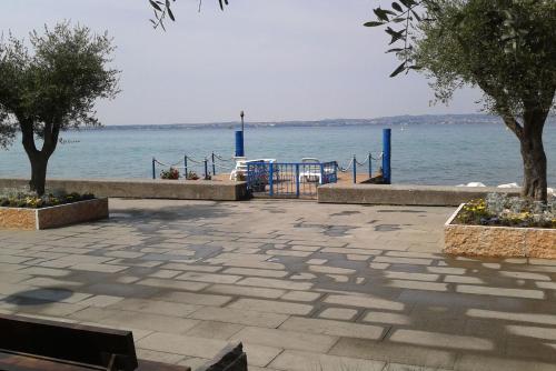 a stone walkway next to the water with trees at Hotel Giardino in Sirmione