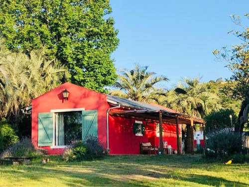 una casa roja con palmeras en el fondo en Casa de campo - retiro con encanto en las sierras, en Minas