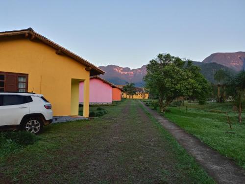 a car parked next to a house with mountains in the background at Pousada Malacara in Praia Grande