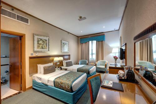 a hotel room with two beds and a desk at Orchid Hotel Al Barsha "Formerly Golden Tulip Hotel Al Barsha" in Dubai