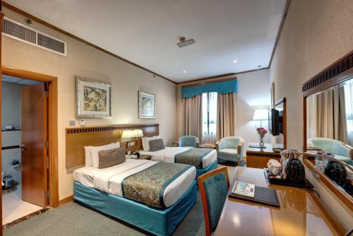 a hotel room with two beds and a desk at Golden Tulip Hotel Al Barsha in Dubai