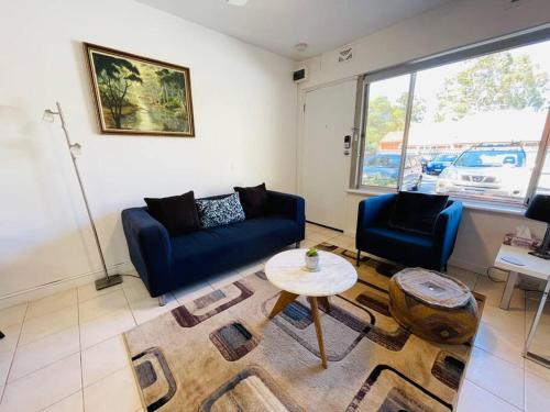 uma sala de estar com dois sofás azuis e uma mesa em TOP LOCATION CONVENIENT QUIET WIFI NETFLIX WINE em Perth