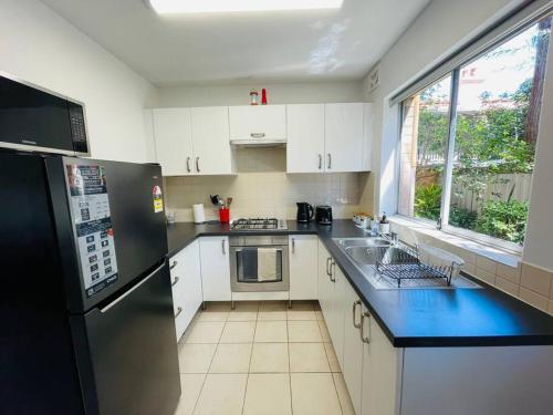 a kitchen with white cabinets and a black refrigerator at TOP LOCATION CONVENIENT QUIET WIFI NETFLIX WINE in Perth