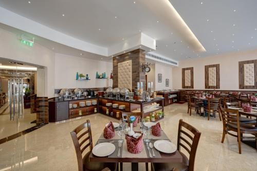 a dining room with tables and chairs in a restaurant at Orchid Hotel Al Barsha "Formerly Golden Tulip Hotel Al Barsha" in Dubai