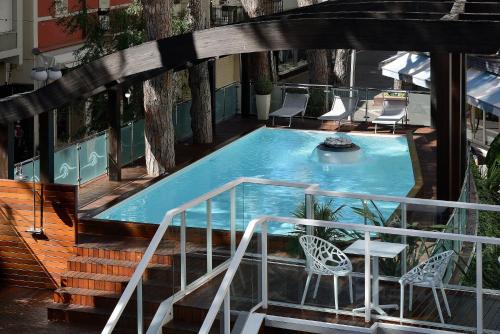 a swimming pool on a balcony with stairs and chairs at Hotel Concord - Nel cuore di Riccione in Riccione