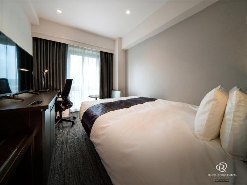 a hotel room with a bed and a desk and a computer at Daiwa Roynet Hotel Kumamoto in Kumamoto