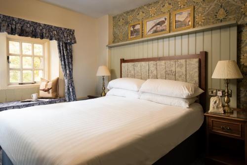Un dormitorio con una gran cama blanca y una ventana en The Pheasant Inn - The Inn Collection Group en Bassenthwaite
