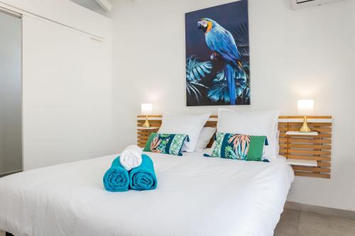 - une chambre dotée d'un lit blanc avec des oreillers bleus et verts dans l'établissement Ti Eden Villas a Saint-Francois, à Saint-François