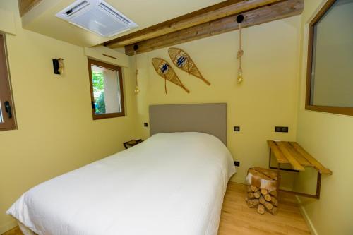 um quarto com uma cama branca e piso em madeira em Gîte Pont-à-Mousson, La Pépinière, Chalet Canada em Pont-à-Mousson