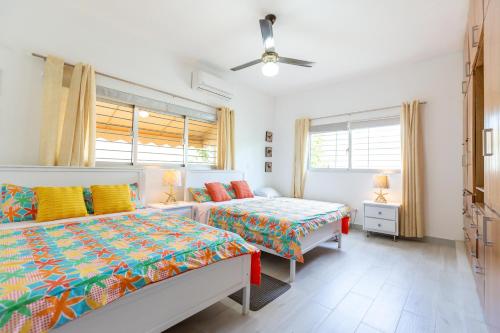 a bedroom with two beds and a ceiling fan at Villa Alida Nagua Pool Beach Dailymaid & Bbq in Matancita