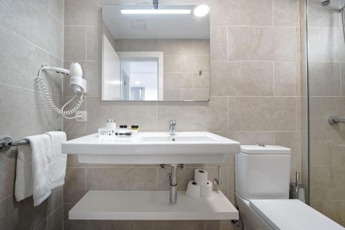 Un baño con lavabo, inodoro y espejo. en ConMar, en San Agustín
