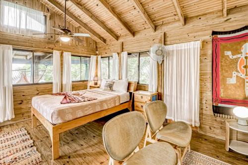 ein Schlafzimmer mit einem Bett und Stühlen in einem Zimmer in der Unterkunft Edge of the World in Dominical