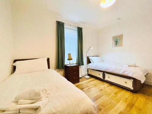 1 dormitorio con 2 camas y ventana en Millerston House, en Glasgow