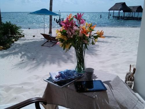 a vase of flowers sitting on a table on the beach at CANCUN PRIVATE APARTMENT in Cancún