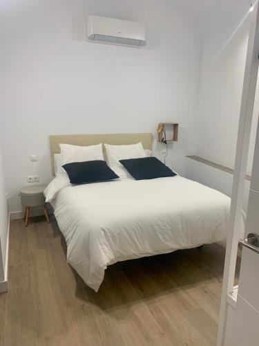 a bedroom with a large white bed with blue pillows at PUERTA DE CACERES Apartamento 2 in Cáceres