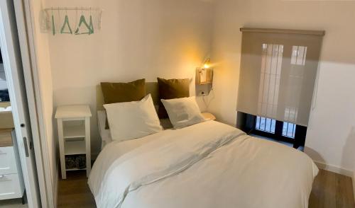 1 dormitorio con 1 cama con sábanas y almohadas blancas en PUERTA DE CACERES Apartamento 2, en Cáceres