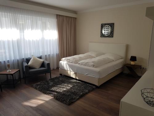 ein Schlafzimmer mit einem Bett, einem Stuhl und einem Fenster in der Unterkunft City Apartments in Krefeld