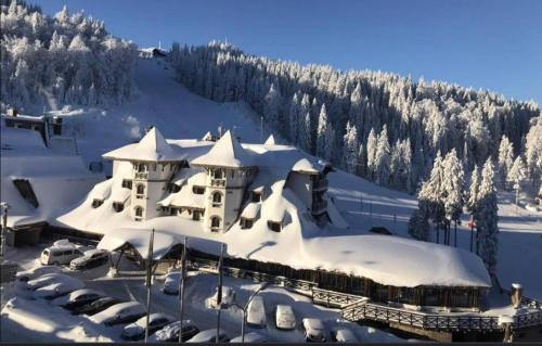 a building covered in snow with cars parked in front at Vučko Apartman U532 in Jahorina
