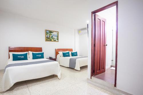 a bedroom with two beds and a mirror at Ayenda Hotel Carivdi in Sincelejo