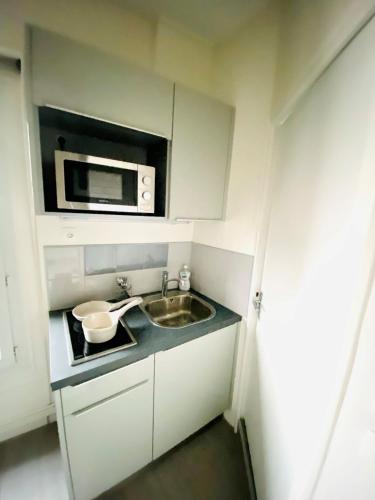 uma pequena cozinha com um lavatório e um micro-ondas em ENGHIEN-LES-BAINS: studio au cœur du centre ville. em Enghien-les-Bains