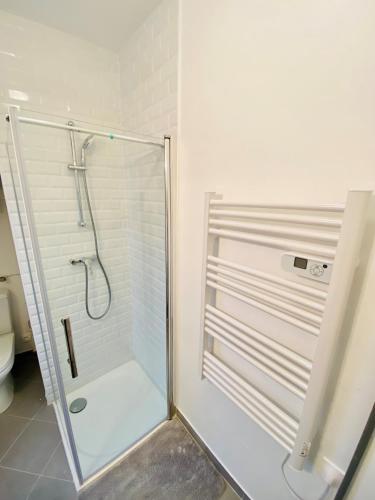 La salle de bains est pourvue d'une douche avec une porte en verre. dans l'établissement ENGHIEN-LES-BAINS: studio au cœur du centre ville., à Enghien-les-Bains