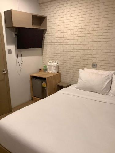 ein Schlafzimmer mit einem weißen Bett und einer Ziegelwand in der Unterkunft CR.HOTEL in Makkasan