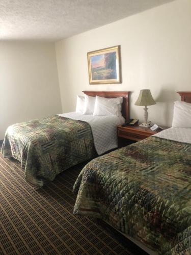 um quarto de hotel com duas camas e uma mesa com um candeeiro em Southgate Hotel em Cambridge