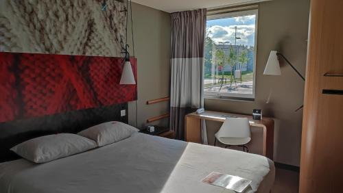 a bedroom with a bed and a desk and a window at ibis Moulins in Moulins