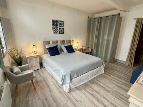 ein Schlafzimmer mit einem Bett mit blauen Kissen und einem Stuhl in der Unterkunft Maison de Roche-Uzès Centre Historique L' Ucetia in Uzès