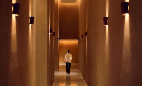 a woman walking down a hallway with lights at Park Hyatt Guangzhou in Guangzhou