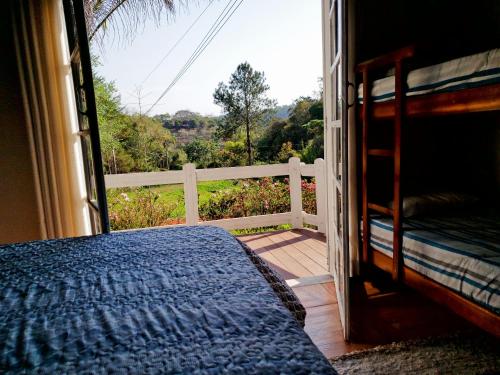 une chambre avec un lit et un balcon avec vue dans l'établissement Casa Grande da Montanha - Sítio Pasangas, à Santo Antônio do Pinhal