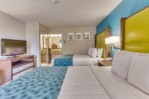 a hotel room with two beds and a flat screen tv at Quality Inn Gulfport I-10 in Gulfport