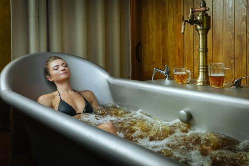 Letna Garden Suites في براغ: امرأة جالسة في حوض الاستحمام مملوء بالرغوة