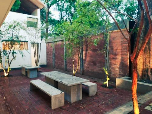 a patio with three benches in front of a brick wall at Arachchi Heritage in Anuradhapura