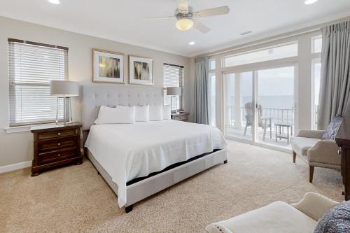 a bedroom with a white bed and a balcony at Windswept by Meyer Vacation Rentals in Gulf Shores