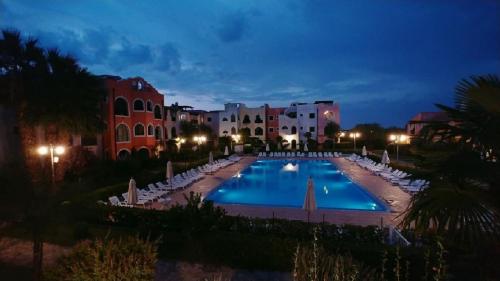 una piscina notturna con sedie e edifici di Basilicata Host to Host - BORGO SAN BASILIO a Marina di Pisticci